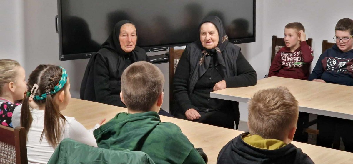 Le donne anziane insegnano ai bambini le canzoni popolari di Mezőszé